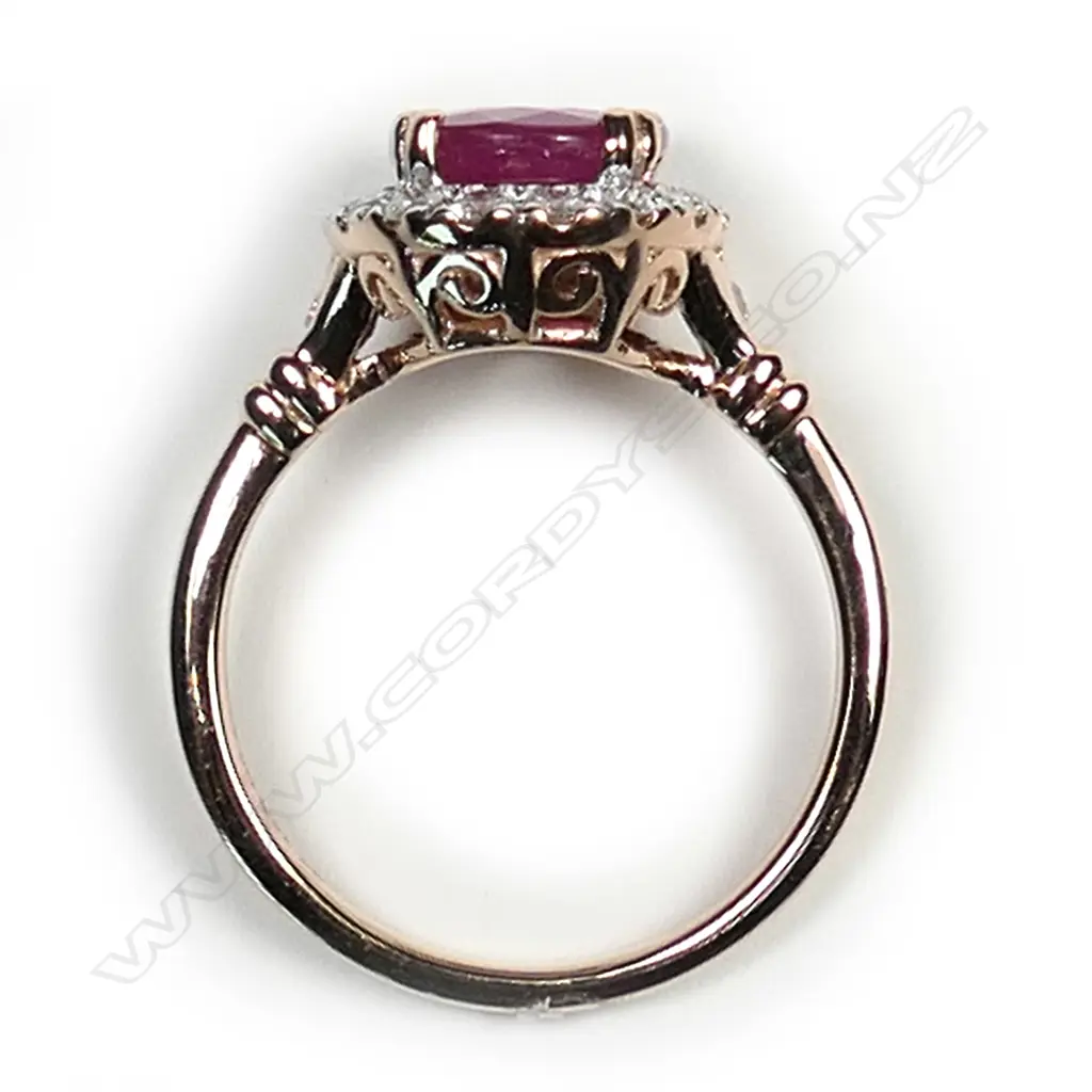 A 14ct rose gold ruby and diamond halo ring, a 2.35ct oval cut red ruby claw set and surrounded by round brilliant cut diamonds (I-J colour, SI1-I2 clarity), with a further brilliant cut diamond to each shoulder, (I-J colour, SI1-SI2 clarity), TDW 0.42ct ring size O. Image 1++