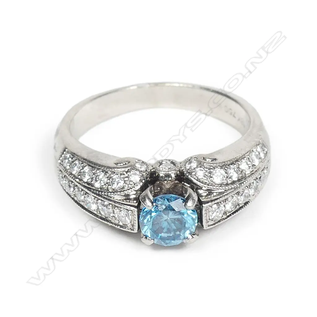 An 18ct white gold treated blue diamond ring, the 'fancy colour' round brilliant cut diamond of 0.53ct in four claw tapered V setting flanked by a triple row of 42 grain set round brilliant cut diamonds, TDW 0.71ct. Valuation available. Image 1++
