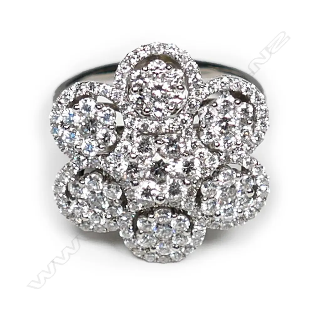 An 18ct white gold and diamond cluster ring, a central cluster of modern round brilliant cut diamonds surrounded by six small clusters of modern round brilliant cut diamonds, set in a decoratively pierced mount, TDW 1.80ct.  Valuation available. Image 1++