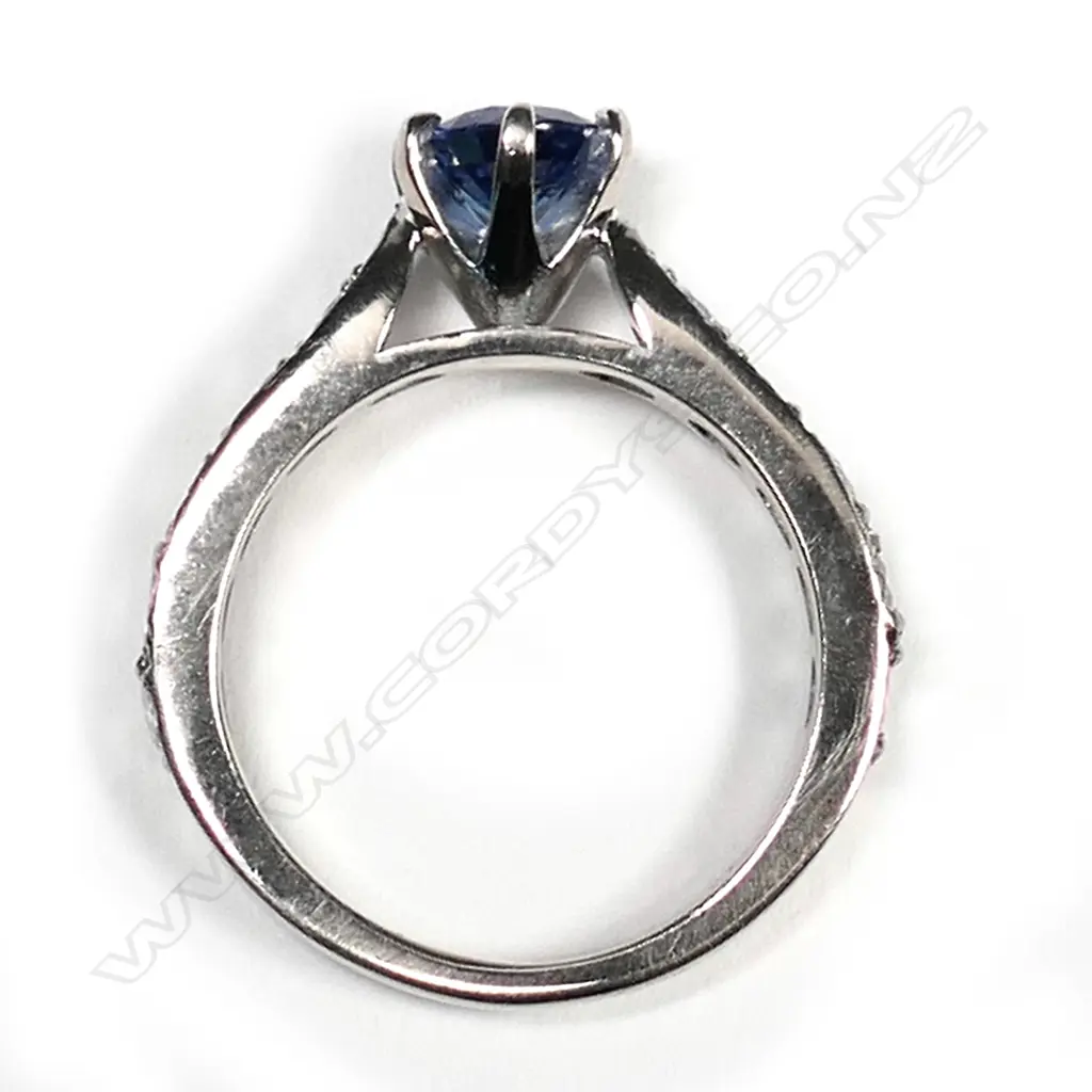 An 18ct white gold sapphire and diamond ring, the 1.17ct oval mixed cut violet blue sapphire claw set with six round modern brilliant diamonds set to each upswept shoulder, TDW 1.22ct.  Valuation available. Image 1++