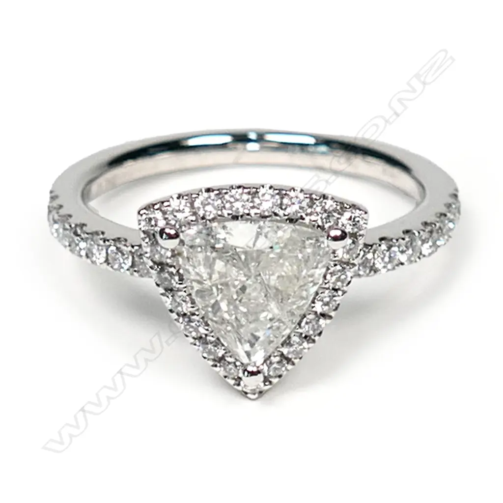 A platinum and diamond vintage style halo ring, a 0.92ct trillion cut diamond (J-K colour, I1-I2 clarity), claw set and surrounded by a halo of twenty-one round brilliant cut diamonds (I-K colour, SI1-I2 clarity), with another fourteen round brilliant cut diamonds set to the band (I-K colour, SI1-I2 clarity), TDW 0.33ct ring size M. Image 1++