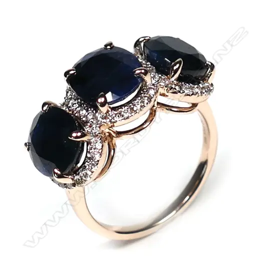 A 14ct rose gold sapphire and diamond halo trilogy ring, three oval cut dark blue sapphires (slightly included), claw set, each sapphire surrounded by a halo of round brilliant cut diamonds (J-M colour, SI1-P1 clarity), TSW 9.31ct, TDW 0.55ct, Ring Size O1/2.