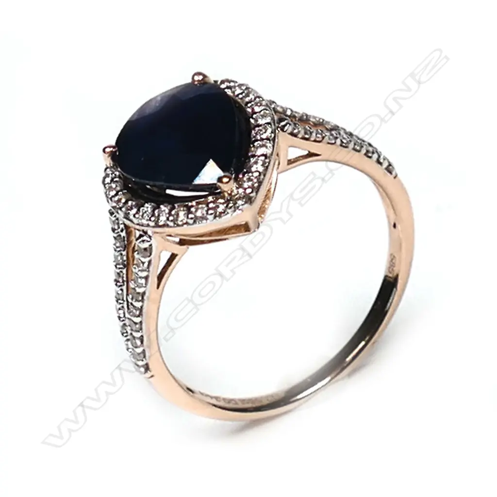 A 14ct rose gold sapphire and diamond halo ring, a 2.58ct pear cut dark blue sapphire (slightly included), claw set and surrounded by a halo of twenty-six round brilliant cut diamonds (J-M champagne colour, SI1-I2 clarity), with a further eighteen diamonds to the split shoulders, (J-M champagne colour, SI1-I2 clarity) TDW 0.34ct, ring size M 1/2. Image 1++