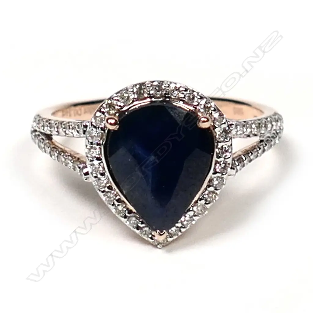 A 14ct rose gold sapphire and diamond halo ring, a 2.58ct pear cut dark blue sapphire (slightly included), claw set and surrounded by a halo of twenty-six round brilliant cut diamonds (J-M champagne colour, SI1-I2 clarity), with a further eighteen diamonds to the split shoulders, (J-M champagne colour, SI1-I2 clarity) TDW 0.34ct, ring size M 1/2. Image 1++