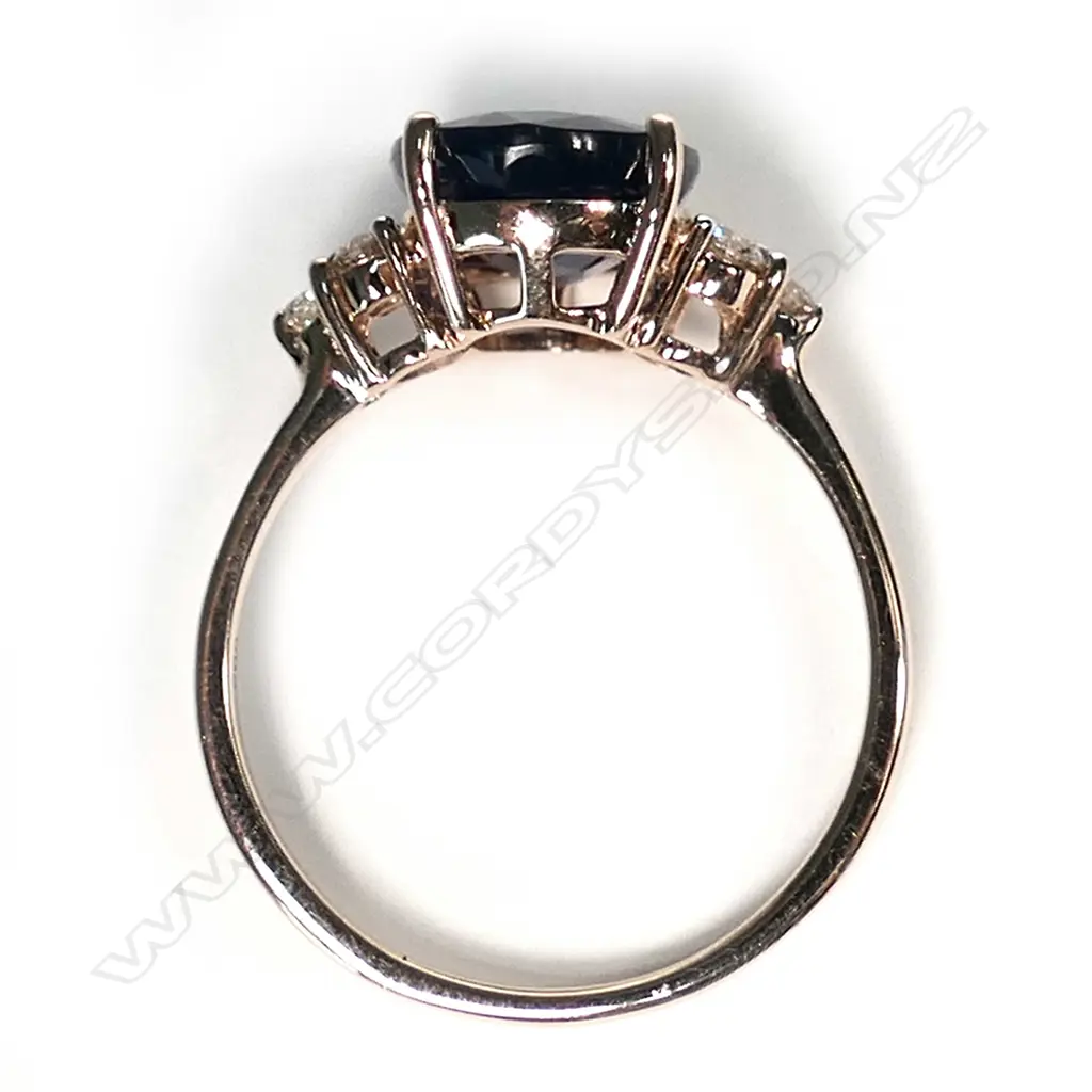 A 14ct rose gold sapphire and diamond ring, a 3.36ct oval cut dark blue sapphire (slightly included), claw set with three round brilliant cut champagne diamonds to each shoulder (0.18ct TDW, SI1-I1 clarity), ring size L. Image 1++