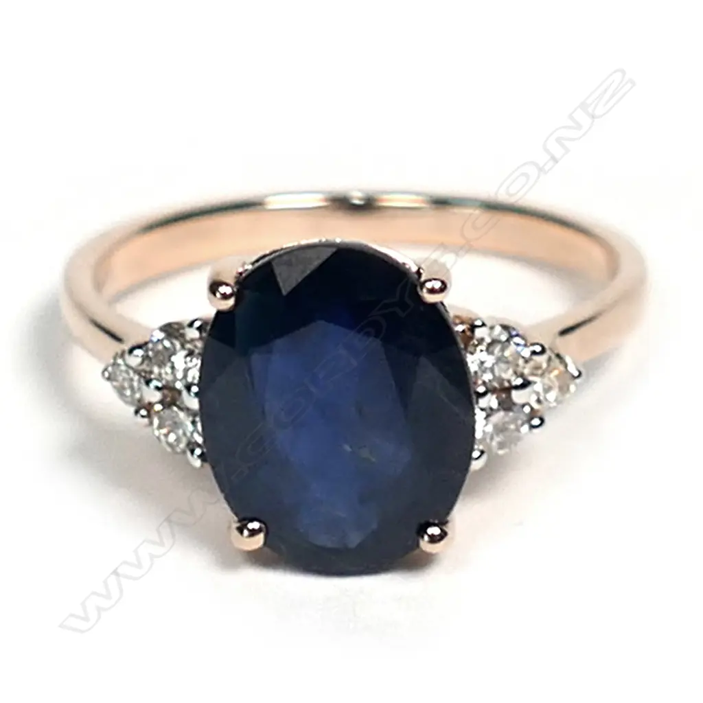 A 14ct rose gold sapphire and diamond ring, a 3.36ct oval cut dark blue sapphire (slightly included), claw set with three round brilliant cut champagne diamonds to each shoulder (0.18ct TDW, SI1-I1 clarity), ring size L. Image 1++