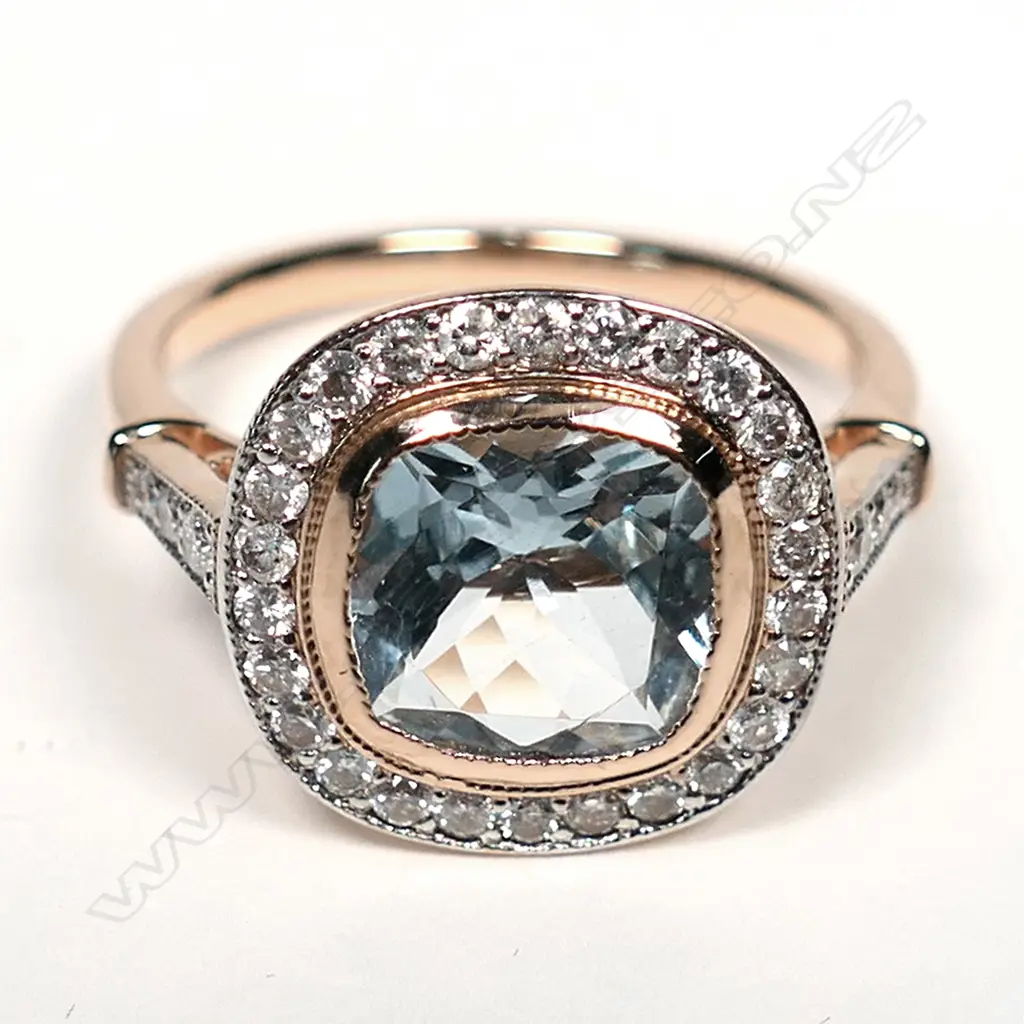 A 14ct rose gold aquamarine and diamond ring, a 1.75ct square cushion cut greyish-blue aquamarine (eye clean clarity), bezel set and surrounded by a halo of twenty-six round brilliant cut diamonds with a further three diamonds to each shoulder, (H-J colour, SI2-I2 clarity), TDW 0.43ct ring size N. Image 1++