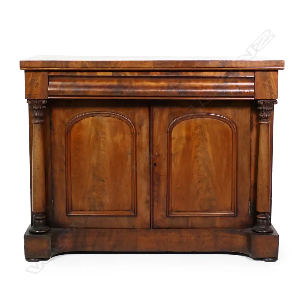 A Regency flame mahogany small sideboard/chiffonier, scrolling back, frieze drawer to the top with full Corinthian columns to each side of two panelled doors, raised on plinth base with squat bun feet.  (Sun fading to one side) 1230 x 575 x 1520mm. Note: This piece does have a scroll back, not shown in photo. Image 1++