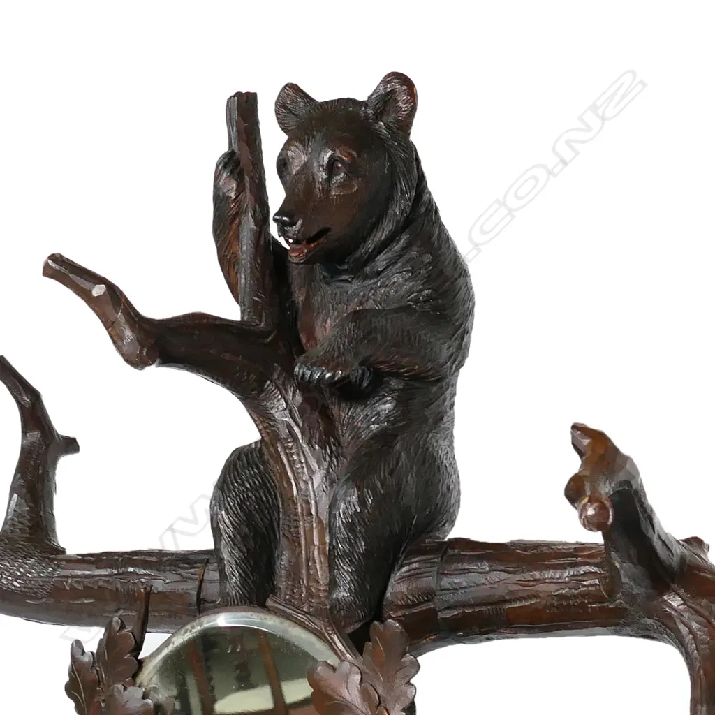 An early 1900s carved Black Forest bear hall/umbrella stand, the mother bear holding the tree trunk and with her cub perched on the top, oak leaf framed mirror to the centre, some evidence of old borer to the right hand side of the base, drip tray absent. (Together with a copy of 'Swiss Carvings, The Art of the Black Forest' which features this design in the chapter on hallstands.) 770 x 540 x 2050mm. Image 1++