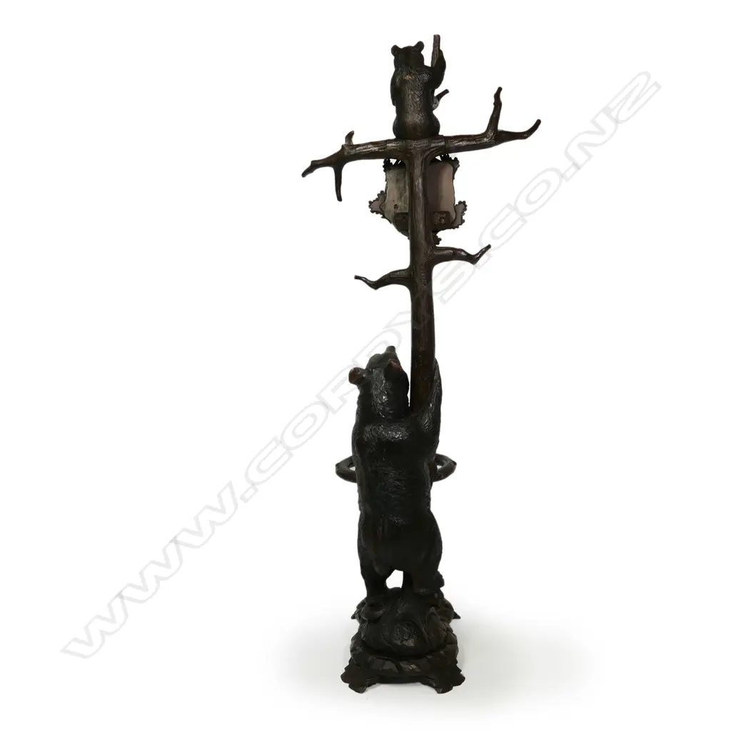 An early 1900s carved Black Forest bear hall/umbrella stand, the mother bear holding the tree trunk and with her cub perched on the top, oak leaf framed mirror to the centre, some evidence of old borer to the right hand side of the base, drip tray absent. (Together with a copy of 'Swiss Carvings, The Art of the Black Forest' which features this design in the chapter on hallstands.) 770 x 540 x 2050mm. Image 1++