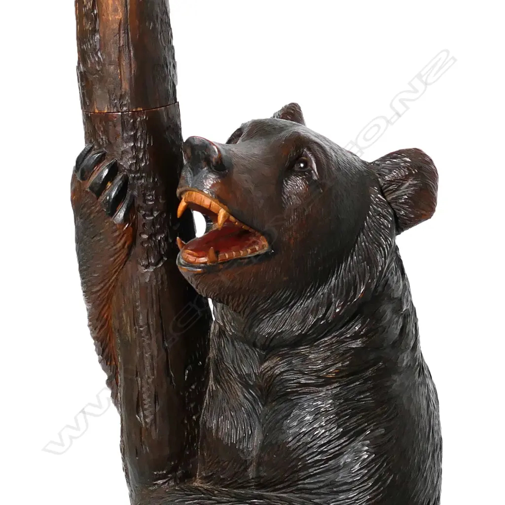 An early 1900s carved Black Forest bear hall/umbrella stand, the mother bear holding the tree trunk and with her cub perched on the top, oak leaf framed mirror to the centre, some evidence of old borer to the right hand side of the base, drip tray absent. (Together with a copy of 'Swiss Carvings, The Art of the Black Forest' which features this design in the chapter on hallstands.) 770 x 540 x 2050mm. Image 1++