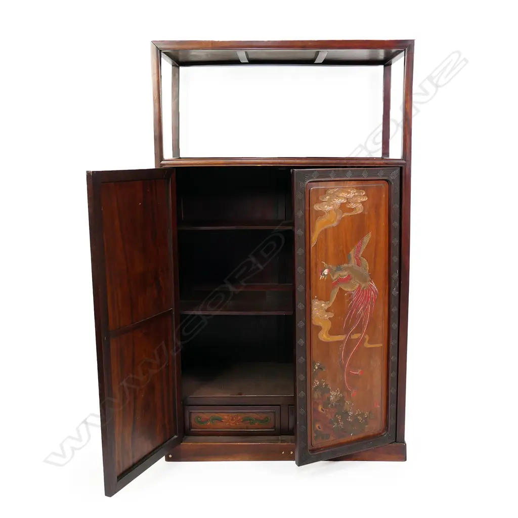 A vintage Chinese rosewood display shelf cupboard, the plain raised top shelf above a pair of tall cupboard doors with carved and painted phoenix, clouds, florals and calligraphy, enclosing three shelves and two drawers. 910 x 440 x 1515mm. Image 1++