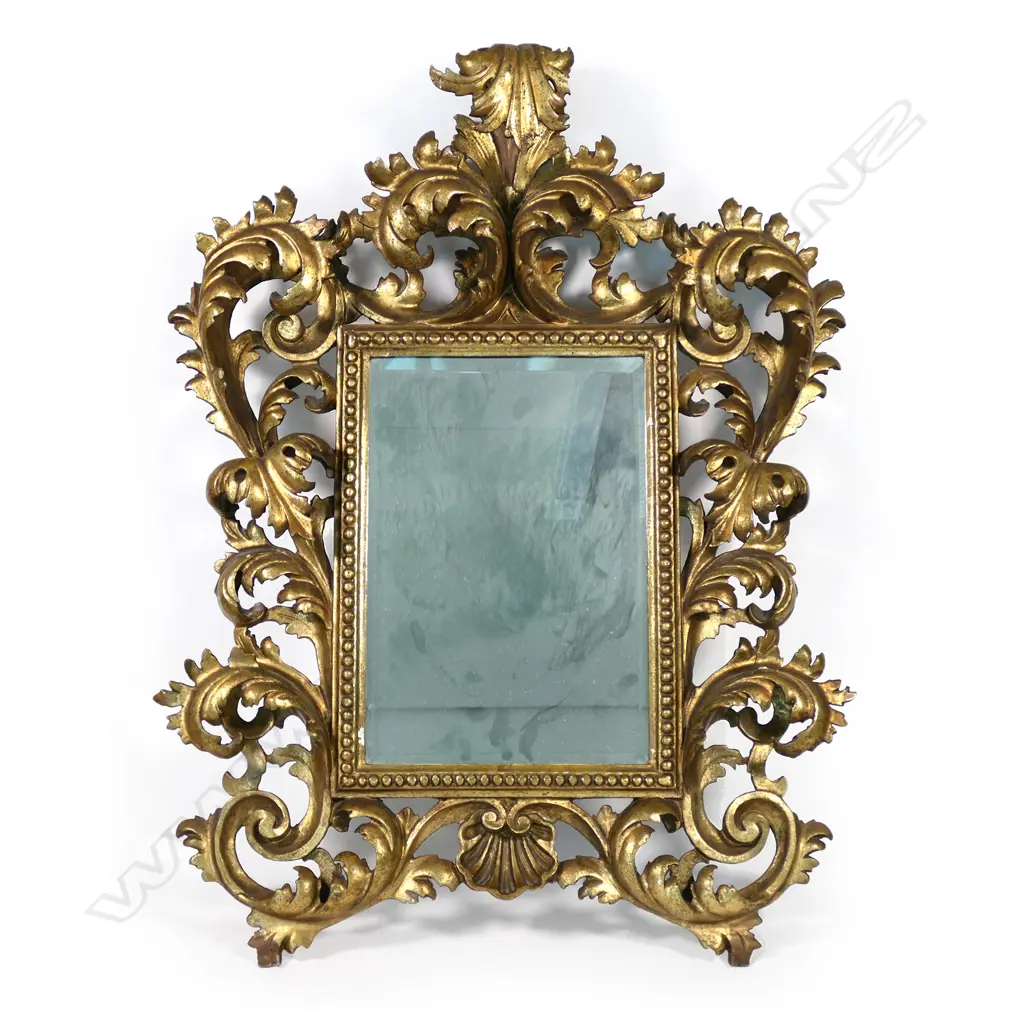 A 19thC gilt framed mirror, an elaborate scrolling frame of leaves and scallop shell, beaded decoration to mirror surround, bevelled mirror.  780 x 580mm. Image 1++