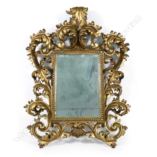 A 19thC gilt framed mirror, an elaborate scrolling frame of leaves and scallop shell, beaded decoration to mirror surround, bevelled mirror.  780 x 580mm.