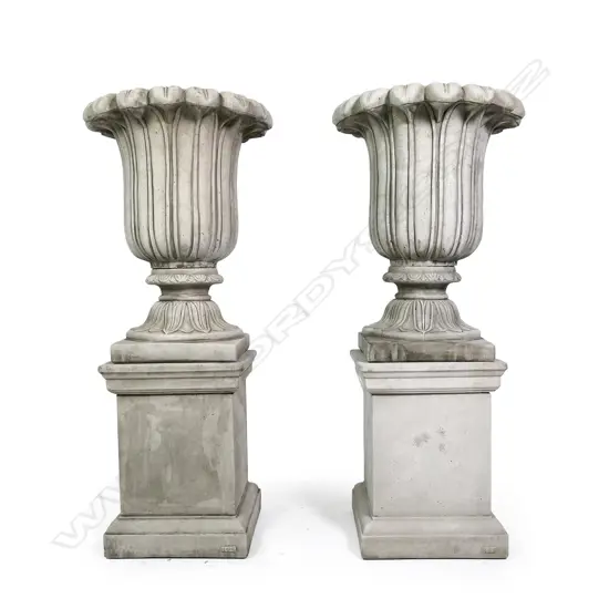 A pair of quality English made cast concrete classical garden urns raised on plinths, vertical fluted detail with swollen leafy flared top rims, the plinths of plain square form. H.1180mm.