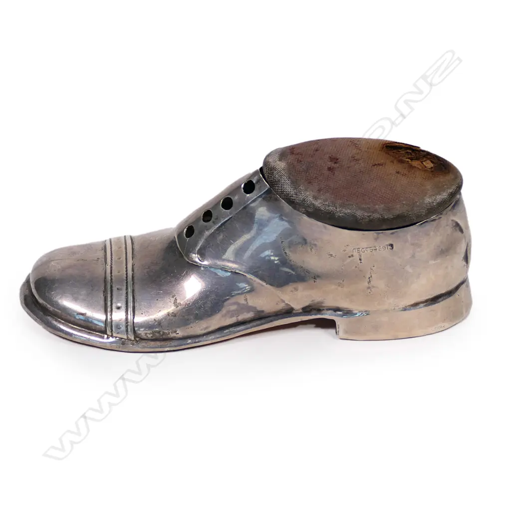 An Edwardian silver pin cushion, in the form of the gentleman's shoe, the pin cushion lifts to reveal a small cavity beneath, some damage to the cushion, Chest 1910. L.125mm. Original oak base. Image 1++