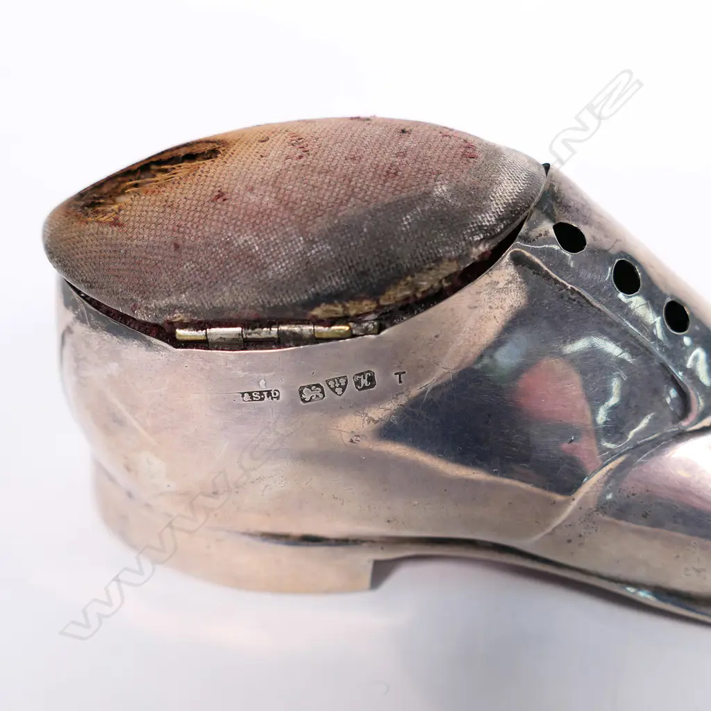 An Edwardian silver pin cushion, in the form of the gentleman's shoe, the pin cushion lifts to reveal a small cavity beneath, some damage to the cushion, Chest 1910. L.125mm. Original oak base. Image 1++
