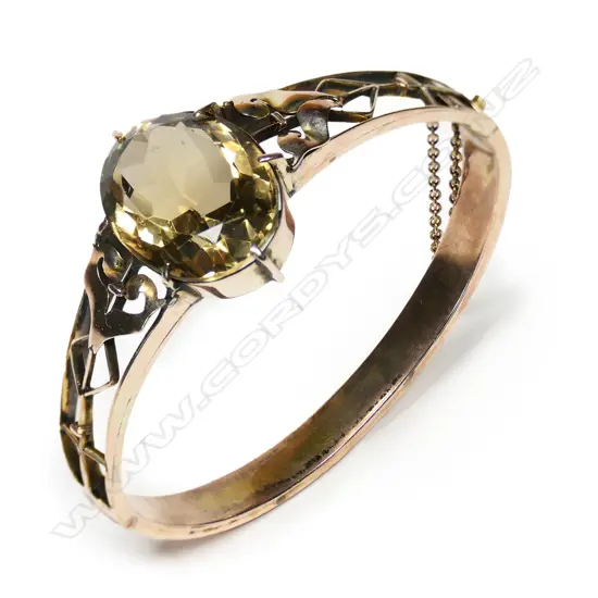 An early 20thC, 9ct rose gold and large citrine hinged bangle,