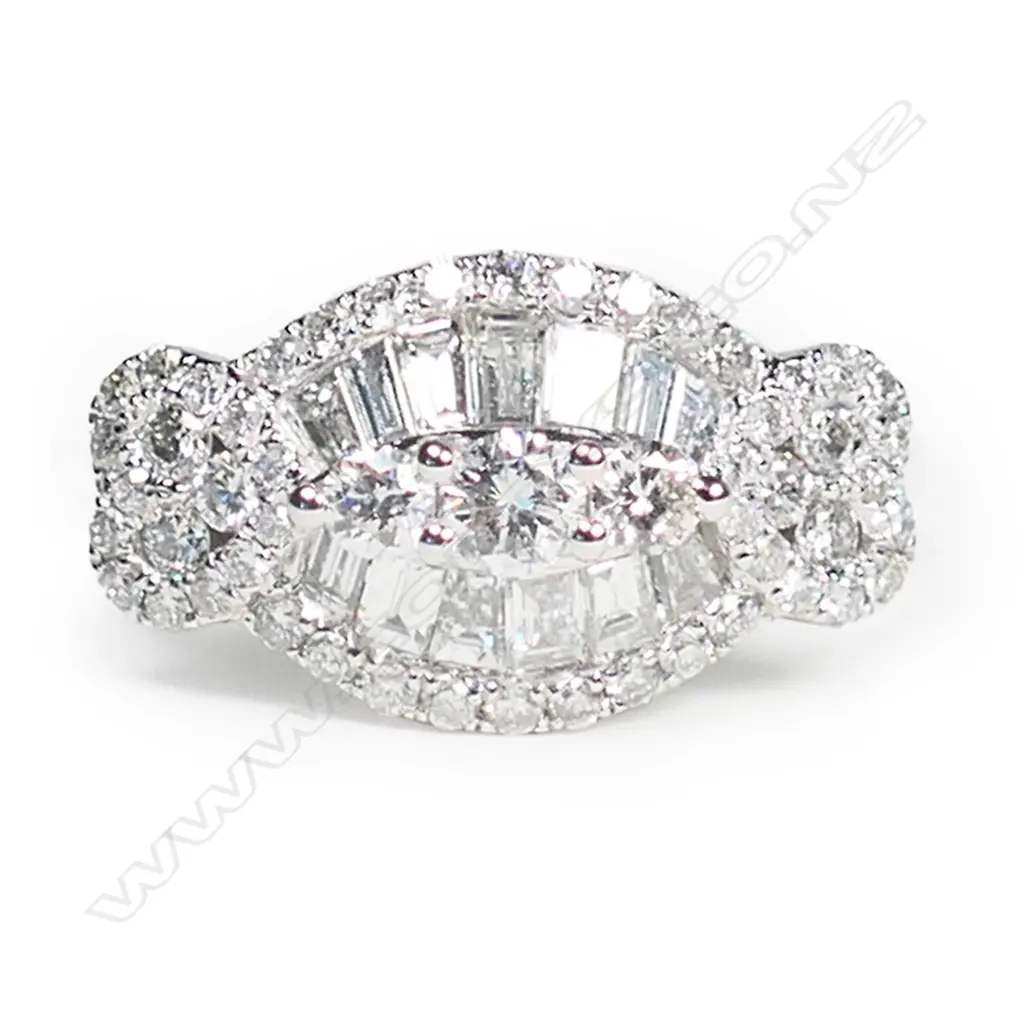 An 18ct white gold and multi diamond ring, formed as twin hearts flanking an oval section set with 53 brilliant and 13 tapered baguette cuts of TDW 1.02ct. Image 1++