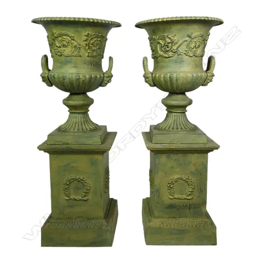 A pair of cast iron garden urns on plinths,