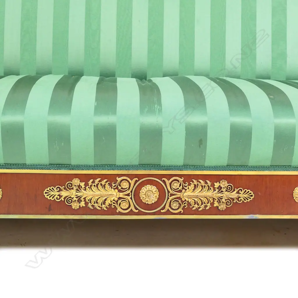 A 19thC French Empire style mahogany sofa, the architectural shaped back, sleigh frame and apron embellished with ormolu palmettes, rosettes, acanthus scrolls and figures, upholstered in a green Empire stripe fabric. Some veneer losses. 2250 x 720 x 1100mm Image 1++