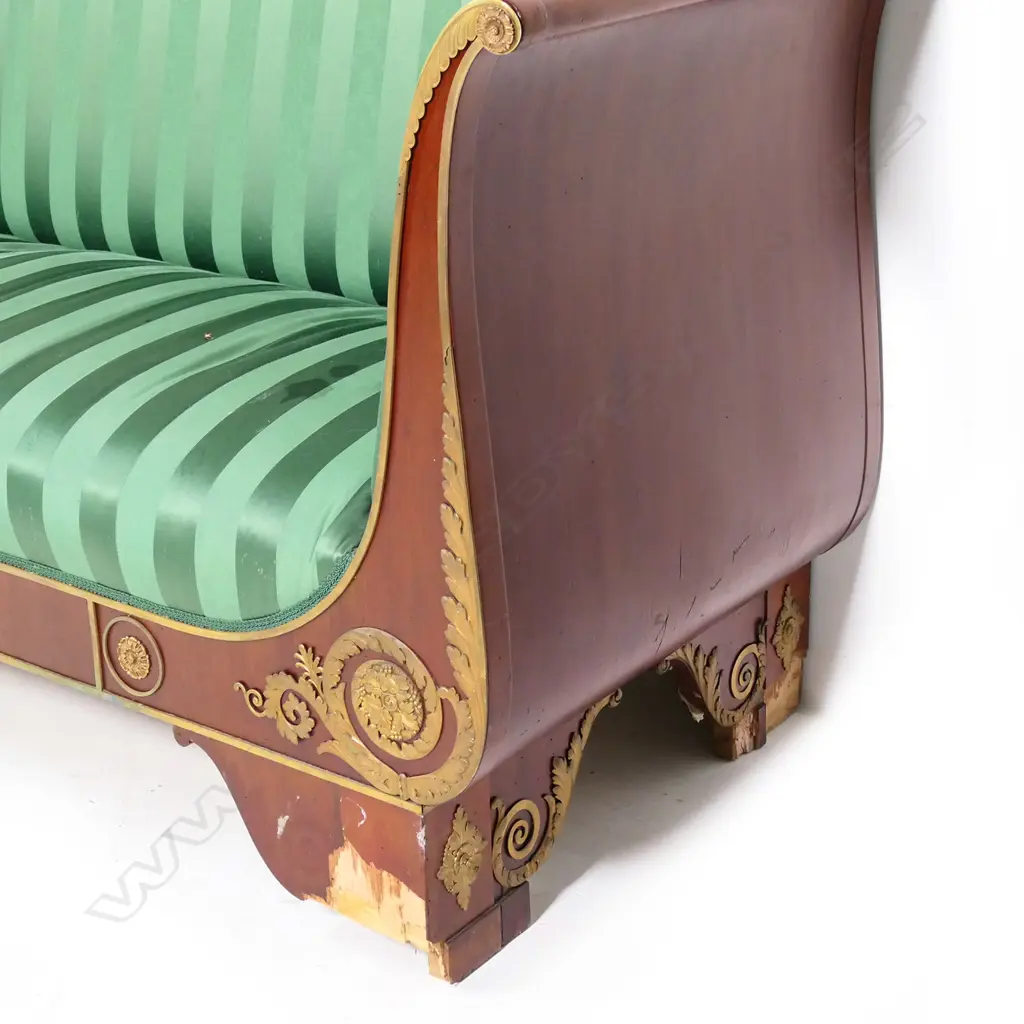 A 19thC French Empire style mahogany sofa, the architectural shaped back, sleigh frame and apron embellished with ormolu palmettes, rosettes, acanthus scrolls and figures, upholstered in a green Empire stripe fabric. Some veneer losses. 2250 x 720 x 1100mm Image 1++