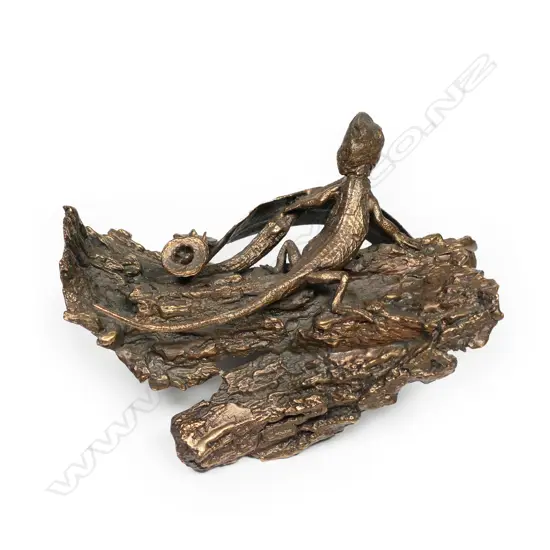 A small bronze sculpture of an Australian lizard,  on bark section with gum nuts,