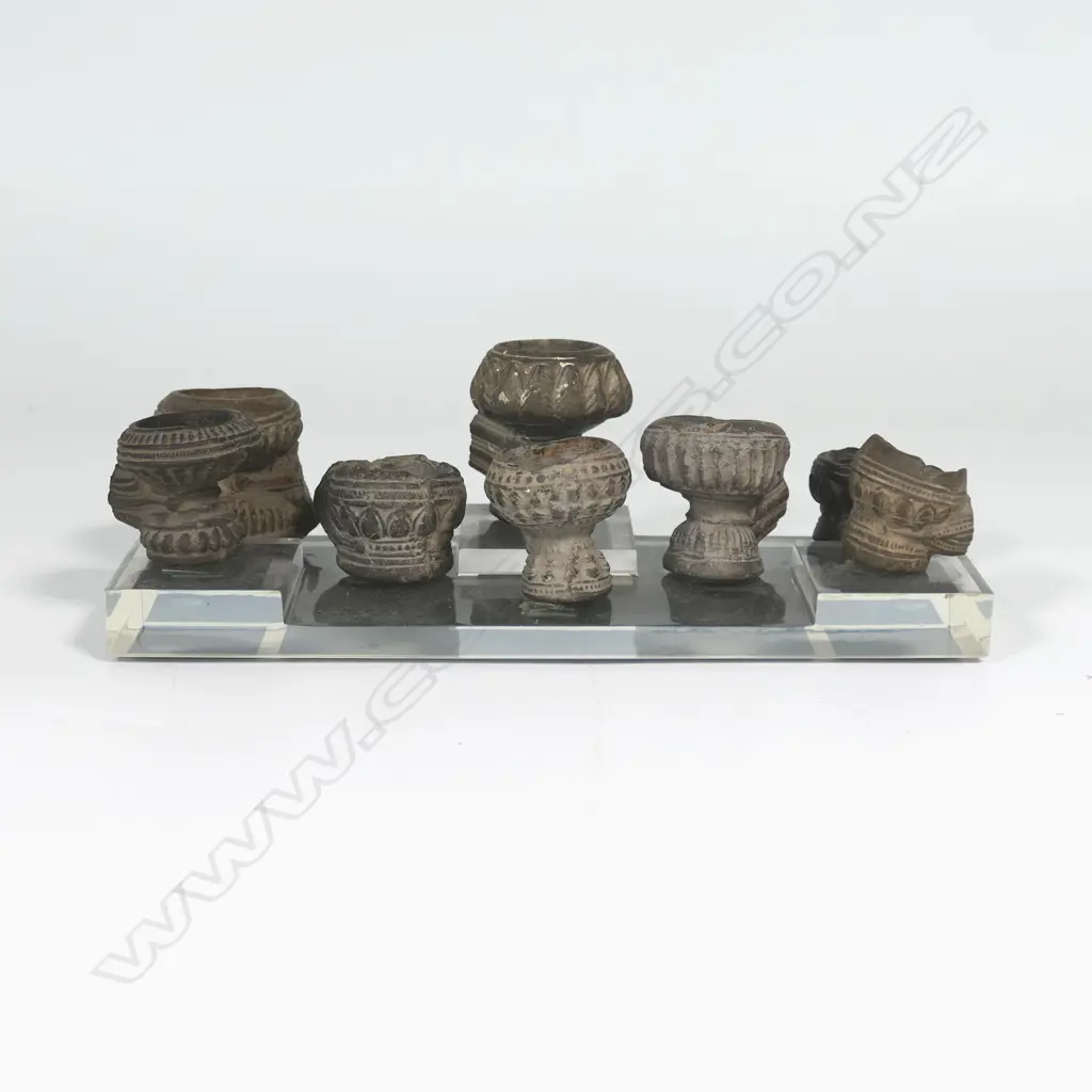 A collection of eight antique Burmese decorated and fired clay opium pipe bowls, the stems broken. Raised on clear Perspex stand. Image 1++
