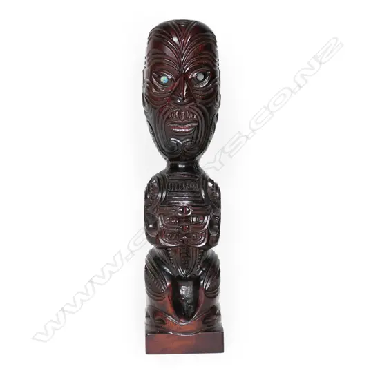 A Māori carved tekoteko figure on a short block base,