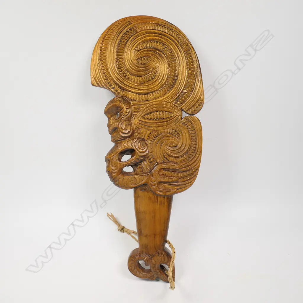 A Māori carved wahaika, double and triple scroll carved blade, full figure to one edge, weku carved butt. c.1980. Image 1++