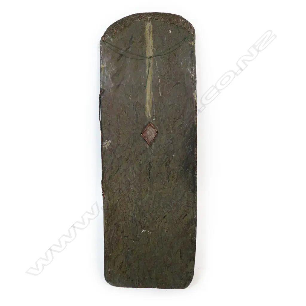 A PNG Highlands Wahgi Valley 'SP Beer' shield, decorated with 'South Pacific SP Lager Beer' details above a symbol flanked by axes. H.1450mm. W.295mm. Note: During the 1980's warfare re-asserted itself in the New Guinea Highlands, the first generation of educated warriors began to use 'new' motifs that often-used words. Designs incorporating Coca-Cola, Pepsi-Cola and SP Beer appeared. This shield with the SP Beer logo also incorporates two metal axes, part of the new armoury of new weapons in warfare. Soon after guns began to be used, and the wooden shields in the main Wahgi Valley all but ceased by about 2000. Provenance: Purchased from Chris Boylan Oceanic Art 2022 for $3,800. The Jorgen Lotz Collection. Image 1++