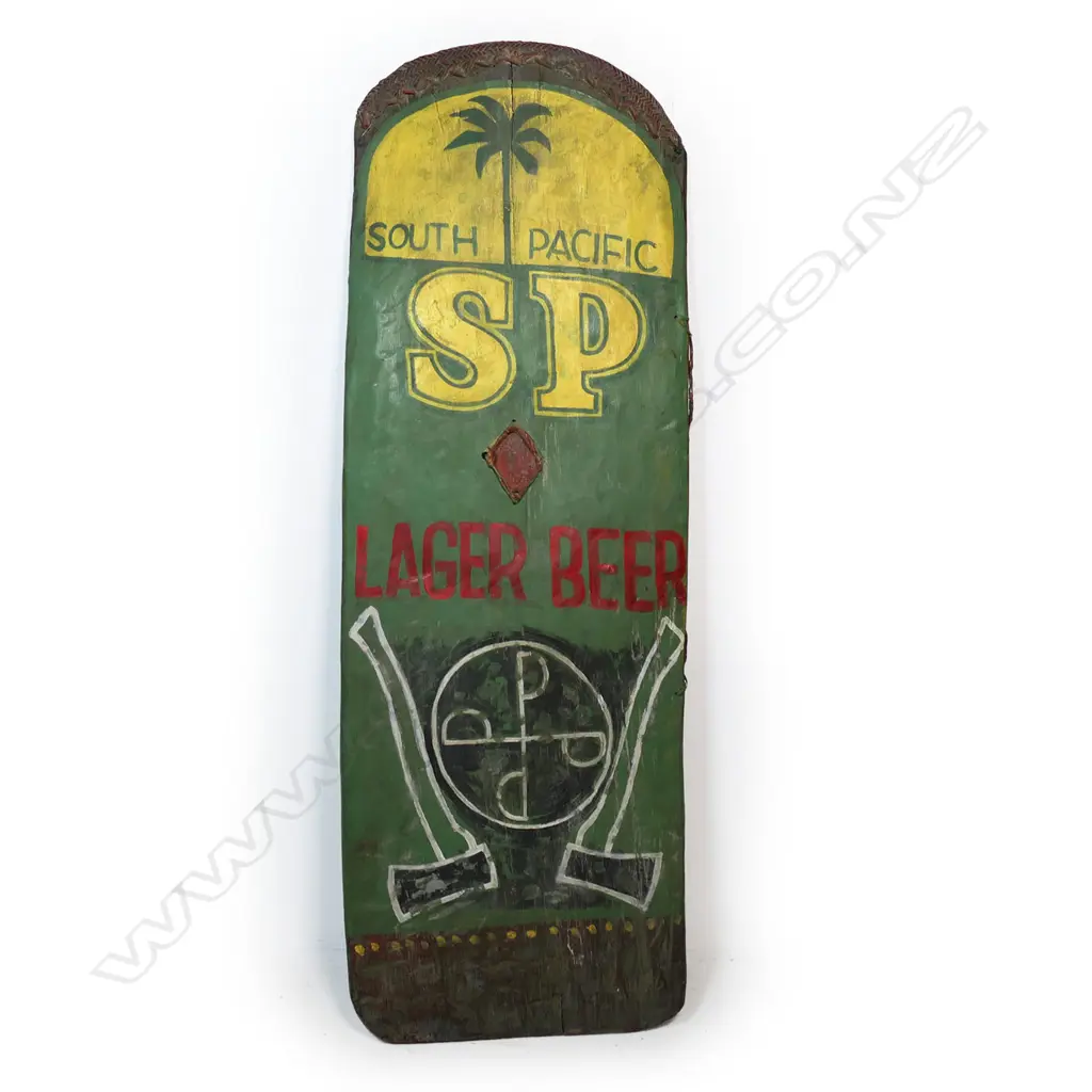 A PNG Highlands Wahgi Valley 'SP Beer' shield, decorated with 'South Pacific SP Lager Beer' details above a symbol flanked by axes. H.1450mm. W.295mm. Note: During the 1980's warfare re-asserted itself in the New Guinea Highlands, the first generation of educated warriors began to use 'new' motifs that often-used words. Designs incorporating Coca-Cola, Pepsi-Cola and SP Beer appeared. This shield with the SP Beer logo also incorporates two metal axes, part of the new armoury of new weapons in warfare. Soon after guns began to be used, and the wooden shields in the main Wahgi Valley all but ceased by about 2000. Provenance: Purchased from Chris Boylan Oceanic Art 2022 for $3,800. The Jorgen Lotz Collection. Image 1++