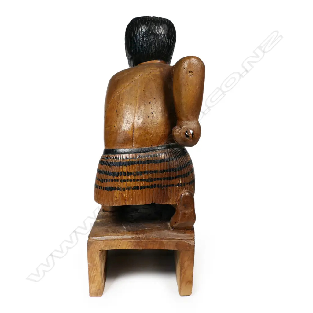 A carved folk art Māori warrior, kneeling with taiaha, carved on block with wheku carved to each side. H.310mm. Image 1++