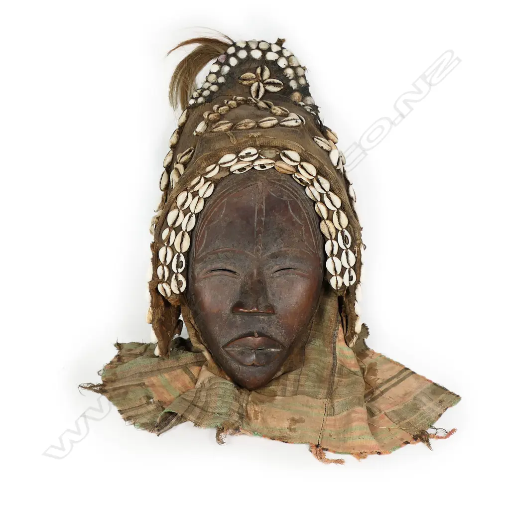 African female Dan mask carved wood with fabric backed head cover highlighted with shells. H.400mm. Provenance: Ex. The Estate of John Perry. Image 1++