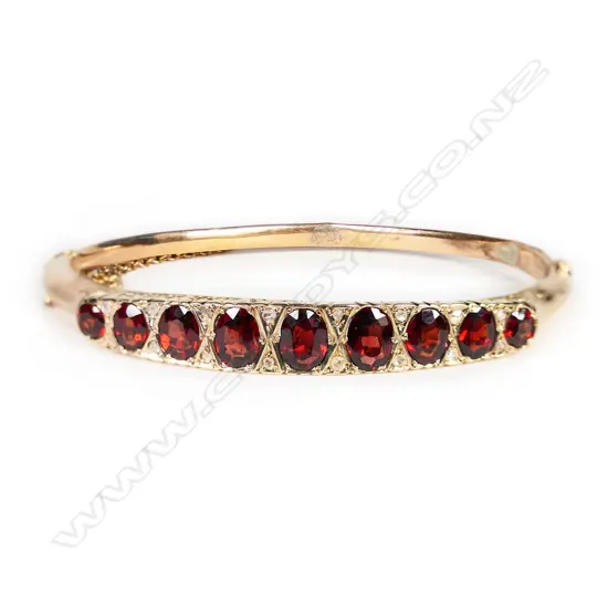 An Edwardian 9ct rose gold garnet and diamond hinged bangle,