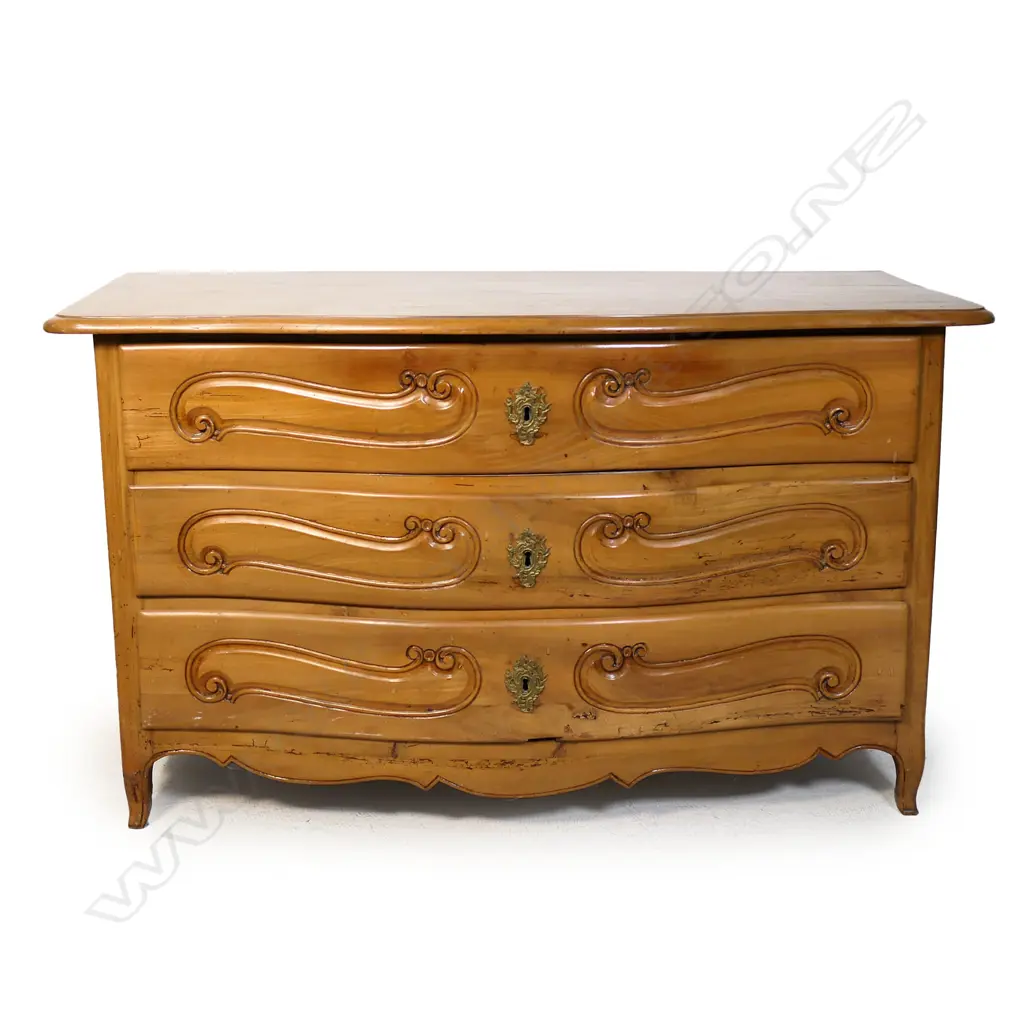 A continental fruitwood chest of drawers. Serpentine shape - three full width drawers with carved detail. Raised on slight cabriole legs (one foot requires attention). 1360 x 680 x 790mm. Image 1++