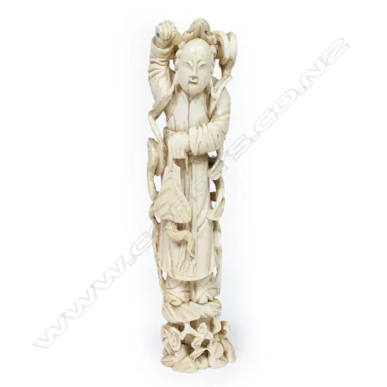 A Japanese ivory figure of a temple guardian, standing bearing crossed swords behind his shoulders, his limbs and body flanked by ribbon scrolls. On pegged base. H.175mm