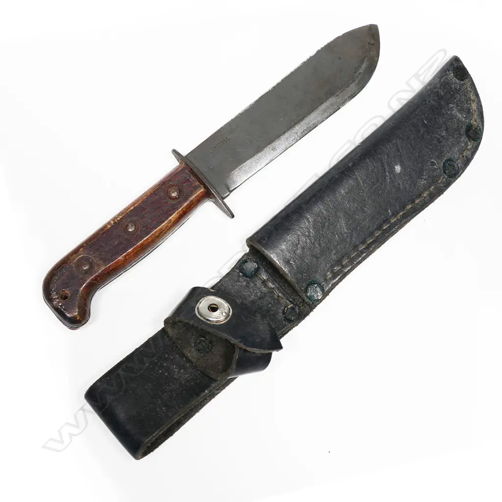Large heavy bowie type knife in leather scabbard. Appears to be the British type D Survival knife. Scabbard appears Australian issue. Blade numbered. L.310mm Image 1++