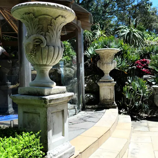 A pair tall concrete classical garden urns on plinth bases