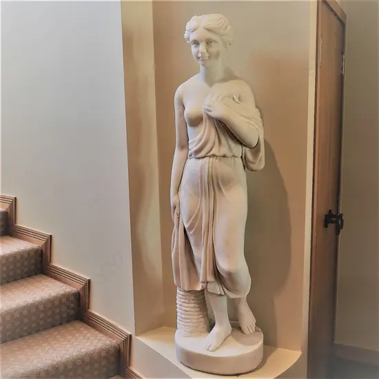 A tall classical carved white marble goddess