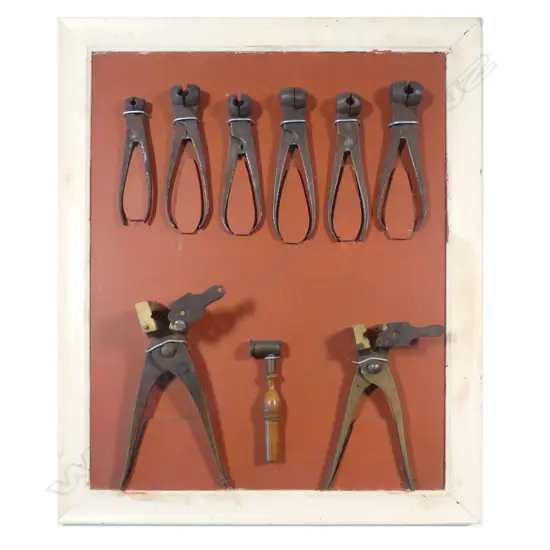 A collection of bullet moulds and powder measure, mounted on display board.