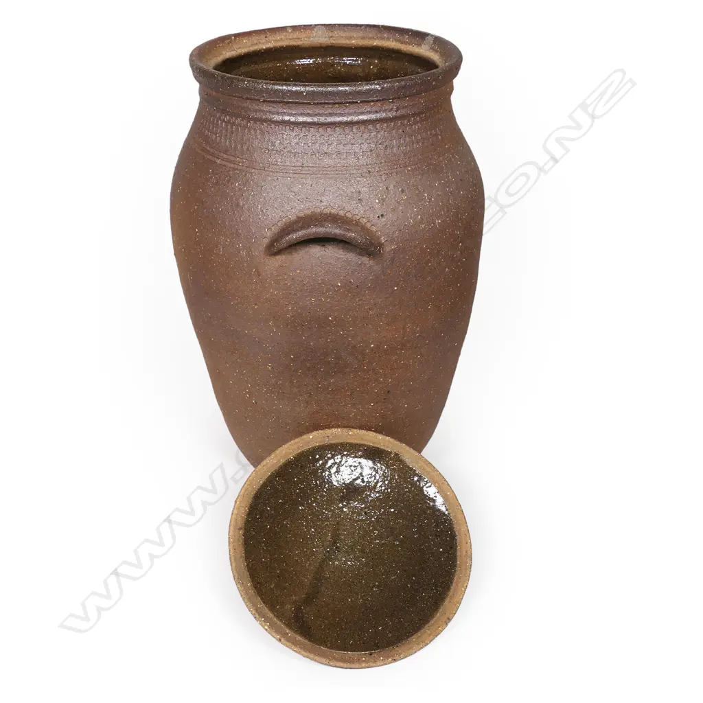 Barry Brickell (1935-2016) lidded storage jar with handles; variable brown and golden toned exterior with a collar of stamped motif. Glazed interior. H.500mm. Image 1++