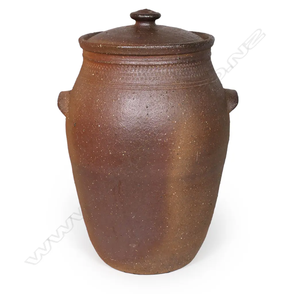 Barry Brickell (1935-2016) lidded storage jar with handles; variable brown and golden toned exterior with a collar of stamped motif. Glazed interior. H.500mm. Image 1++