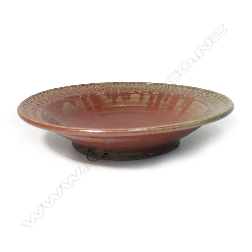 Mirek Smisek red glazed wall charger; the rim with impressed with diamond and triangular repeating motif. Impressed potter's mark to reverse and with rope suspension. Dia.400mm. Image 1++