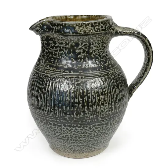 Mirek Smisek early salt glazed jug with a mottled grey/brown glaze and band of finely incised pattern to middle. Impressed potter's mark. H.170mm