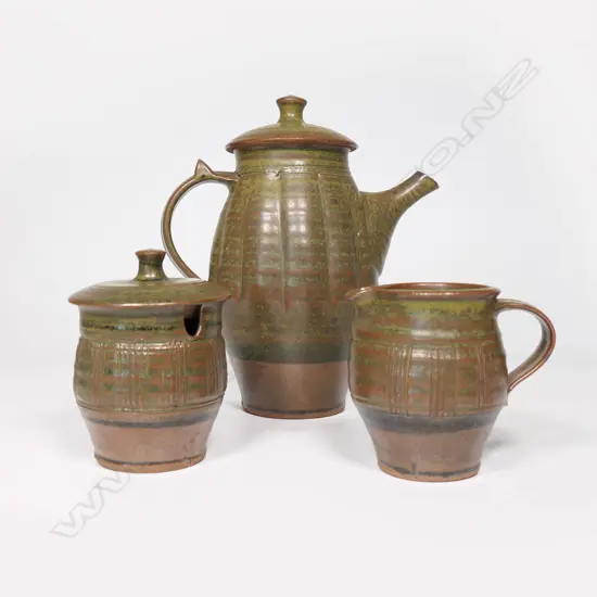 Peter Stichbury (1924-2015) three-piece coffee set - comprising coffee pot, lidded sugar and cream jug. Rock ash glaze. Vertical incised detail. Impressed potter's mark. H.240mm (coffee pot).