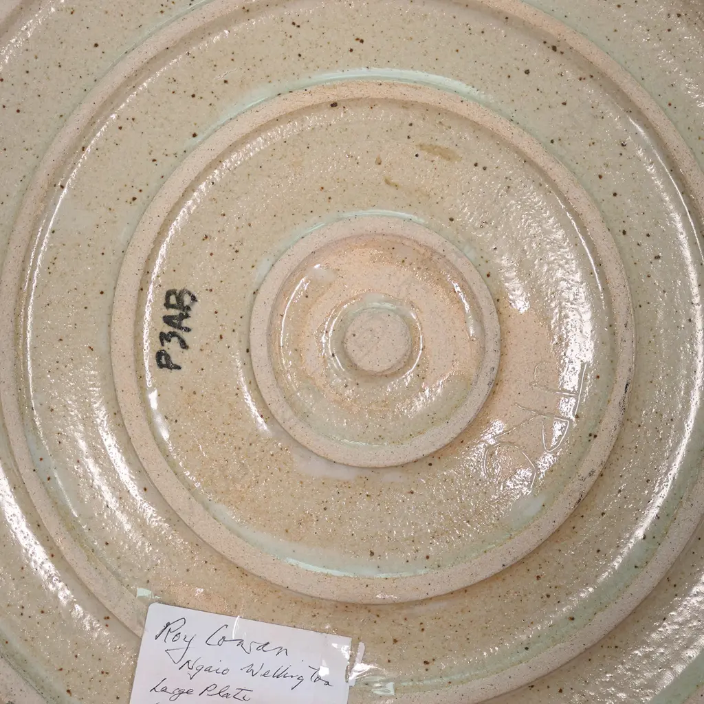 A large Roy Cowan pottery platter decorated with native flora and fauna designs together with iconic NZ subjects, various colours on a stone toned ground, etched initials to base. Dia.395mm. Image 1++