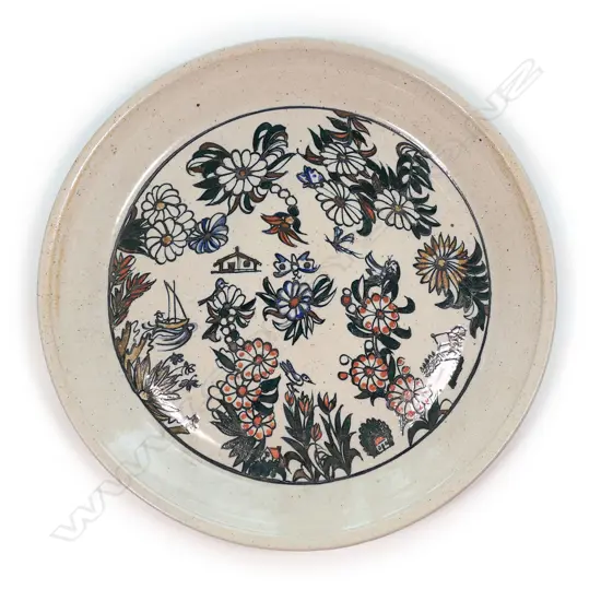 A large Roy Cowan pottery platter decorated with native flora and fauna designs together with iconic NZ subjects, various colours on a stone toned ground, etched initials to base. Dia.395mm.