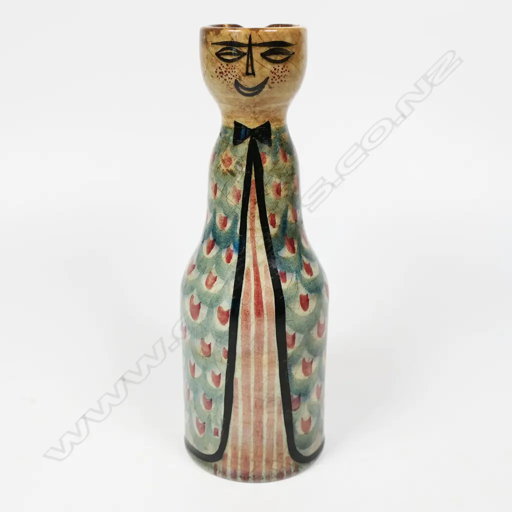 Frank Carpay for Crown Lynn figural oil bottle. The cylinder body decorated with restrained repeated fabric motif and stylised facial detail - pouring lip to rear. HANDWERK H.9-7 signature and Crown Lynn Tiki stamp to base. H.170mm. Image 1++