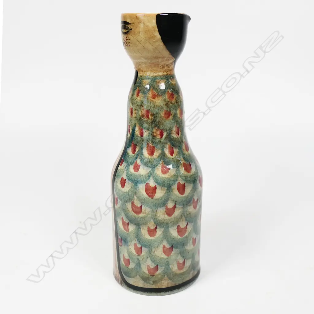 Frank Carpay for Crown Lynn figural oil bottle. The cylinder body decorated with restrained repeated fabric motif and stylised facial detail - pouring lip to rear. HANDWERK H.9-7 signature and Crown Lynn Tiki stamp to base. H.170mm. Image 1++